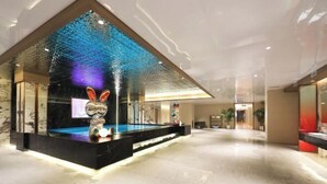 Een ruime lobby met een modern ontwerp, inclusief een fontein in het midden en decoratieve details.