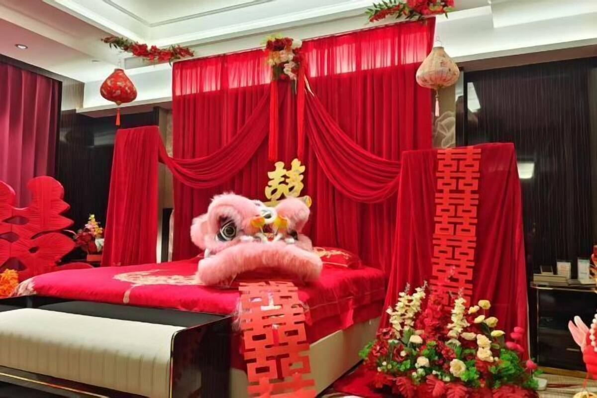 Un lit avec des rideaux rouges, un mur d écoratif et un arrangement floral.