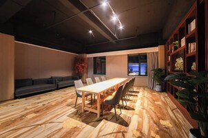 Un salón de conferencias con una larga mesa, sillas, un sofá y una estantería.