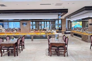 A spacious dining area with marble flooring, multiple dining tables, and chairs.