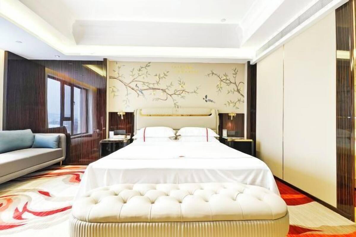 Une chambre d’hôtel moderne, dotée d’un grand lit, d’un canapé et d’une fresque murale décorative.