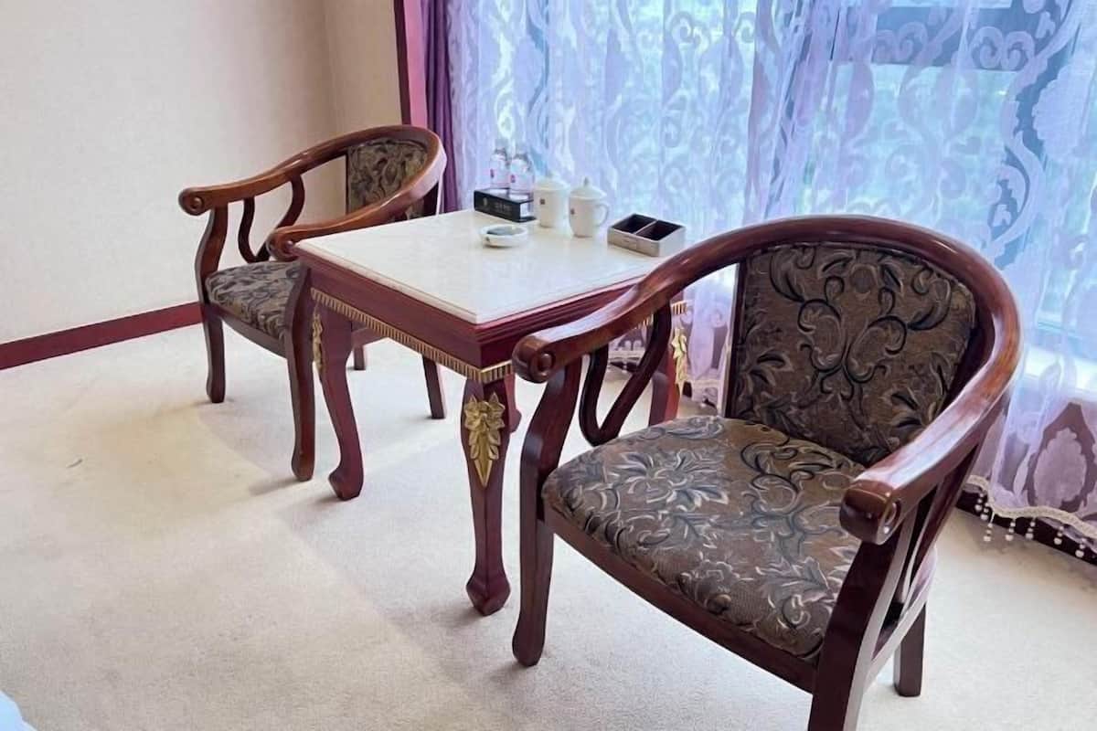 Un coin repas comprenant deux chaises en bois et une table, agrémenté d’une nappe décorative et d’un vase avec des fleurs.