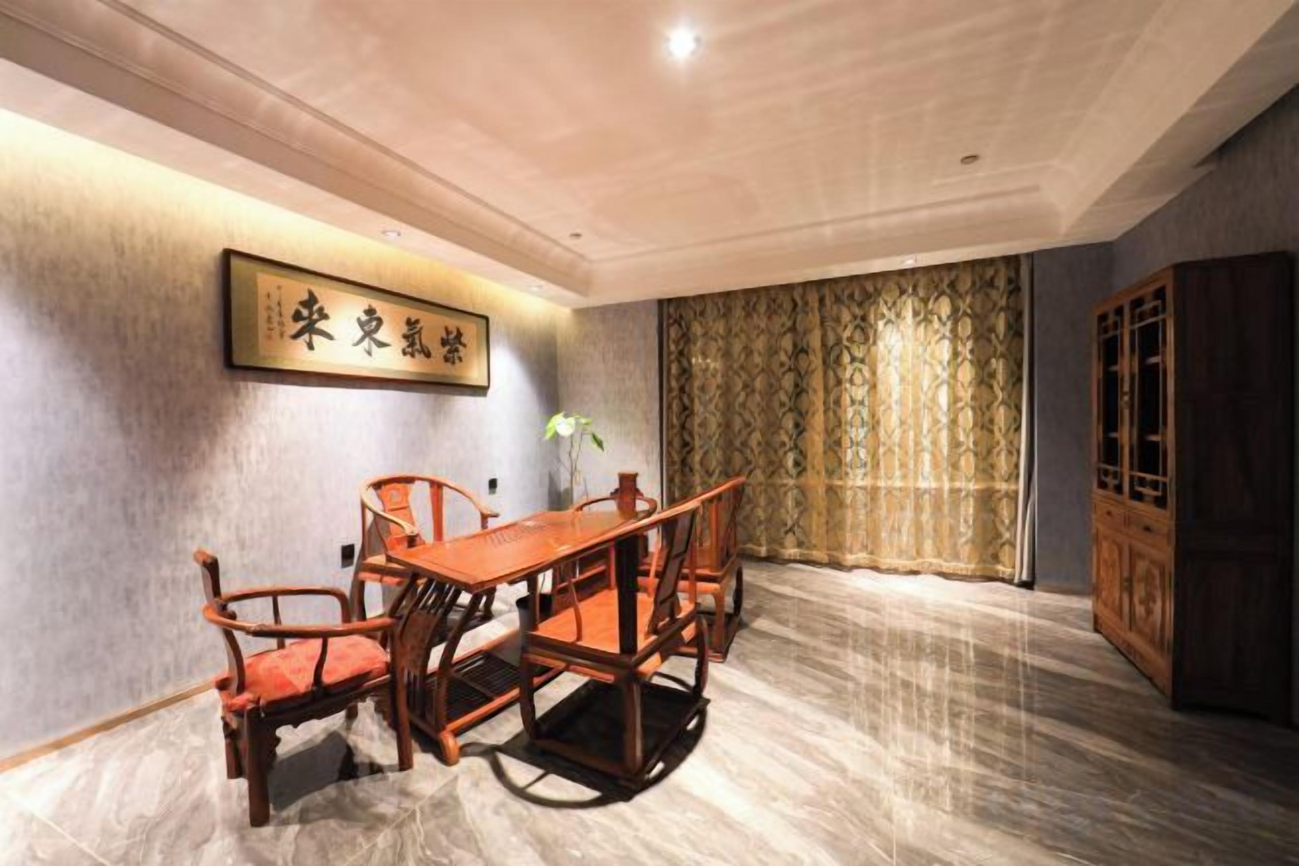 A room with a dining table and chairs, a decorative wall piece, a curtain, and a traditional wooden cabinet.