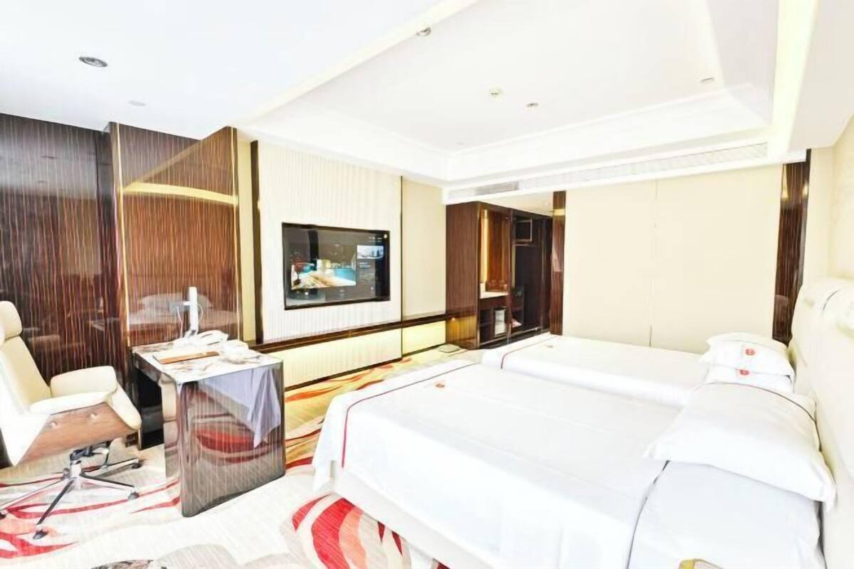 Une chambre d’hôtel équipée d’un lit, d’un bureau, d’une chaise, d’une télévision et d’un mini-bar.