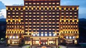 Een meerlaags hotel met een symmetrische gevel, grote ramen en een opvallende entree.