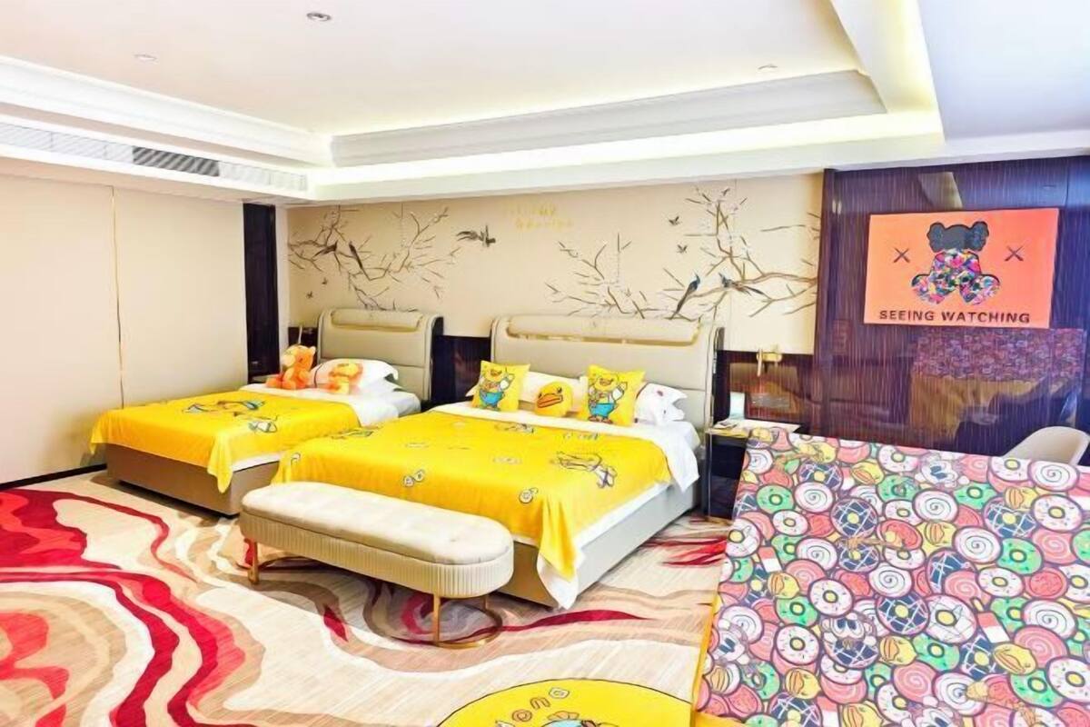 Une chambre d’hôtel avec deux lits, une grande moquette à motifs et un mur orné d’une fresque représentant un arbre.