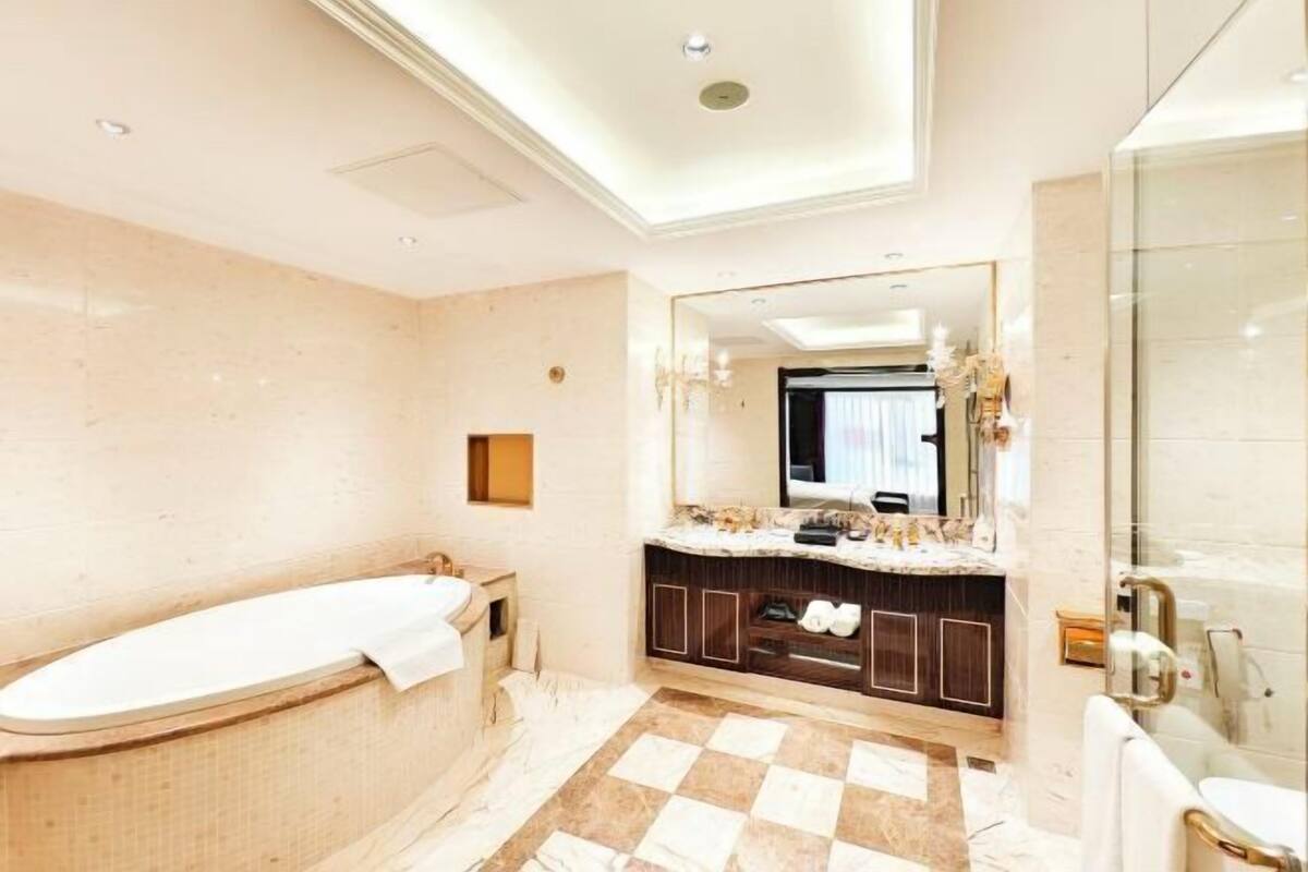 Une salle de bain moderne avec une baignoire sur pieds, un meuble-lavabo avec un miroir et un carrelage à motifs géométriques.