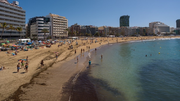 Ein Strand mit einem Hotel im Hintergrund.