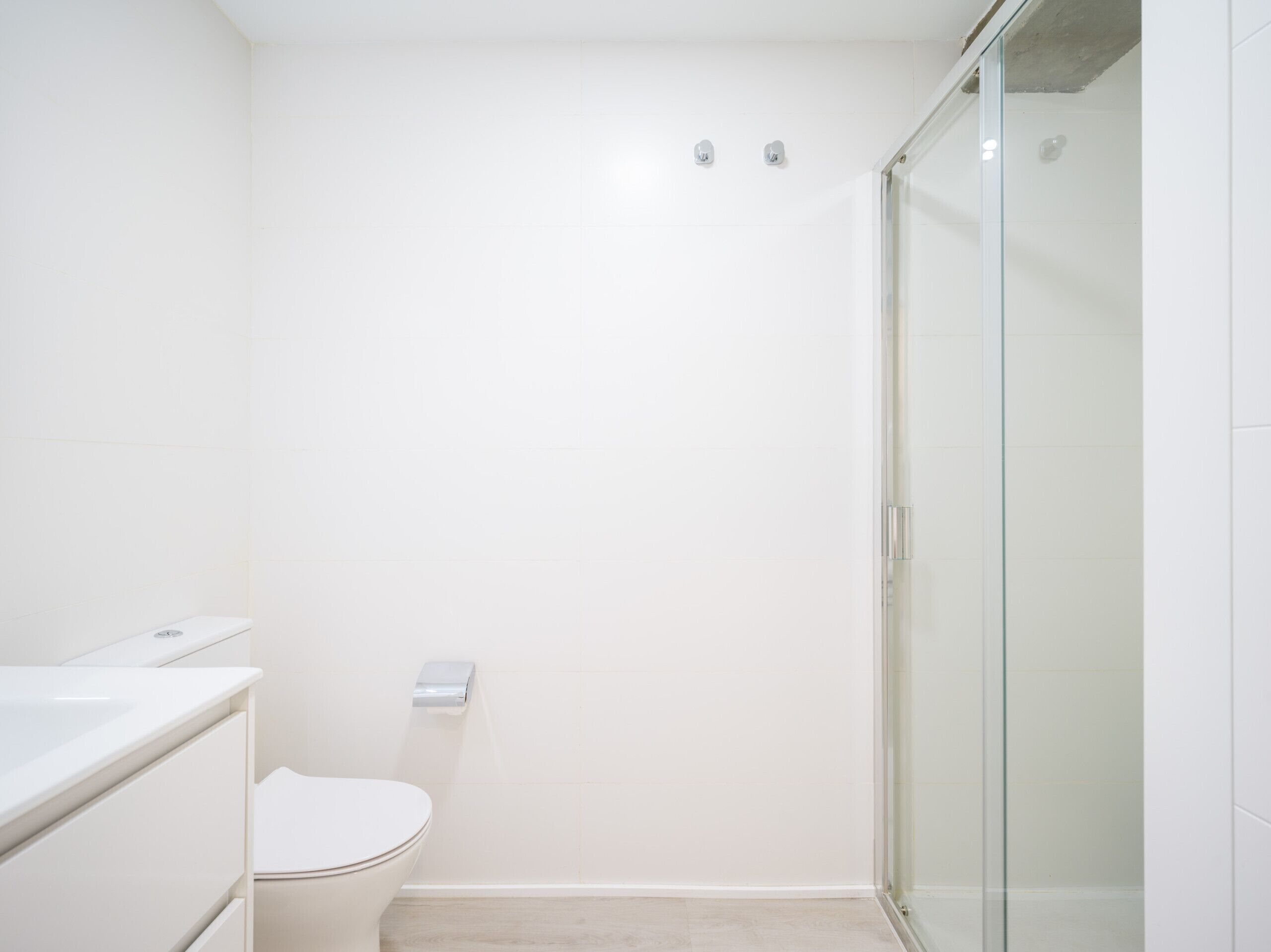 Un baño con inodoro, cabina de ducha de cristal y lavabo blanco.