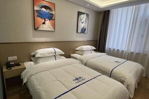 Une chambre d’hôtel avec deux lits, une table de chevet avec un téléphone et des œuvres d’art accrochées aux murs.