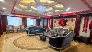A well-lit living room with a chandelier, two sofas, a coffee table, and a patterned rug. - Tianxing Hotel (Lingshi)