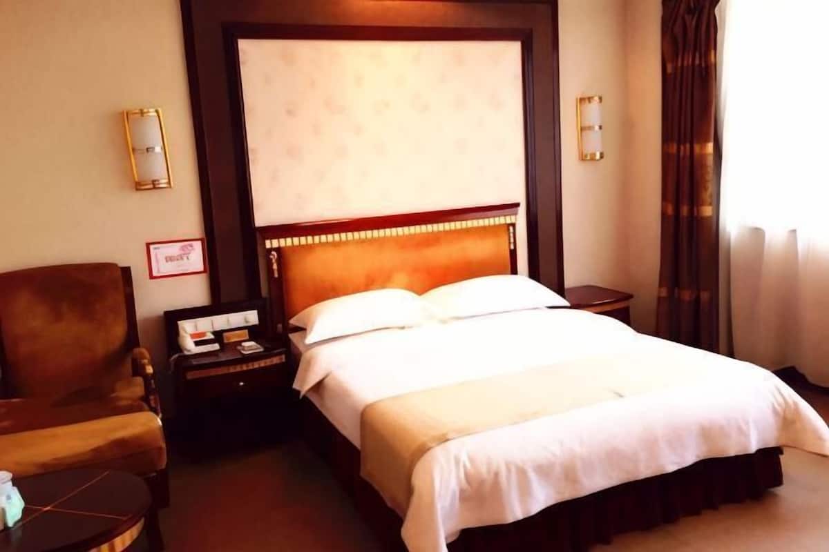 A hotel room with a bed, a chair, a nightstand, and a lamp.