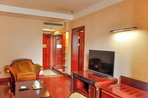 Une chambre d’hôtel avec une table basse en bois, un canapé, une télévision et une porte rouge.
