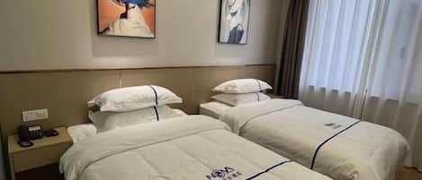 A hotel room with two beds, a bedside phone, and artwork on the wall.