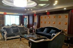 A living room with a sofa, a coffee table, and a patterned carpet. - Tianxing Hotel (Lingshi)
