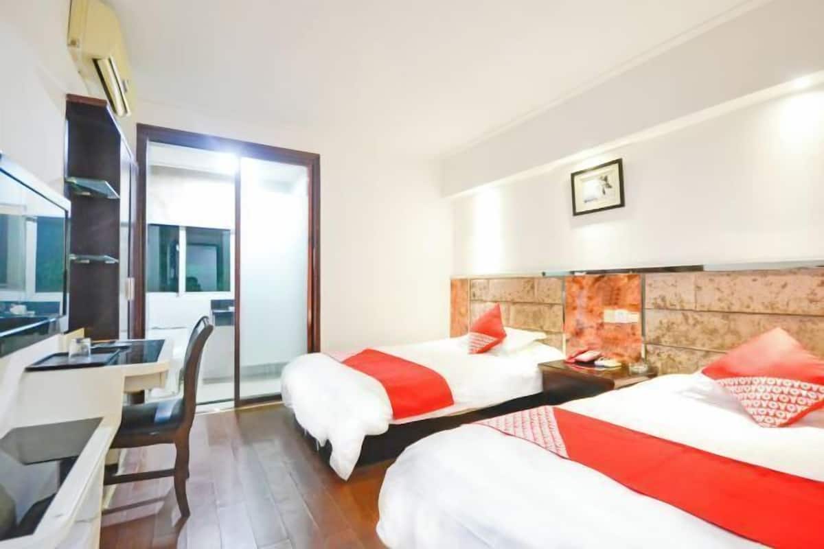 A hotel room with two beds, a desk, and a chair.