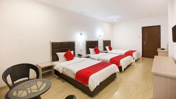 Une chambre d’hôtel avec trois lits, une petite table et une chaise.