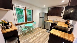 A compact kitchen with a window, a refrigerator, a dishwasher, and a sink. - Modern Beach Retreat–Pet Friendly + Prime Location (Grand Haven)