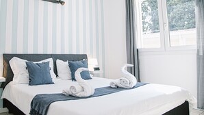 A neatly made bed with white and blue bedding, a headboard, and two wall-mounted lamps. - Firenze Dream Homes - Mona Lisa (Firenze)