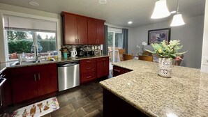 Eine moderne Küche mit Granit Arbeitsplatten, Edelstahlgeräten und Holzschränken.