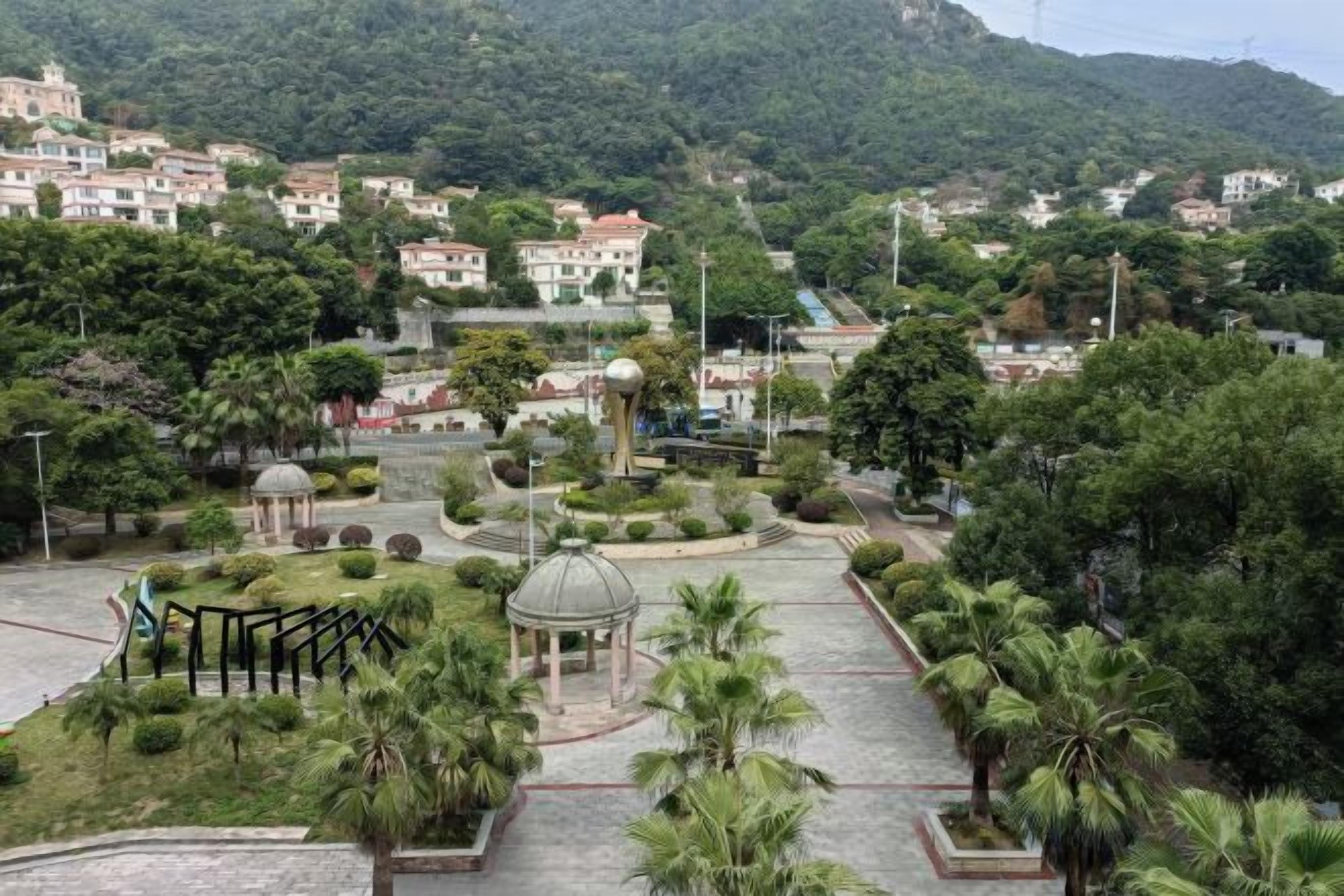 A park with a gazebo, palm trees, and a water tower.