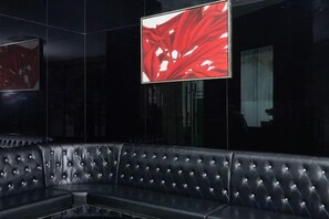 A black leather sofa in a dimly lit room with a large flat-screen TV mounted on the wall. - Beijiang Inn (Qingyuan)