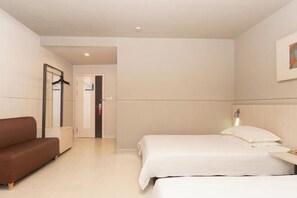 A hotel room with a bed, a sofa, and a door leading to a bathroom.