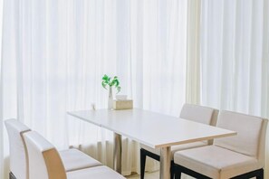 A dining area with a table and chairs, a vase with a plant, and sheer curtains. - Beijiang Inn (Qingyuan)