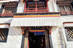 A traditional building with a prominent entrance, ornate decorations, and a tiled roof. - Shambhala Palace Hotel (Lhasa)