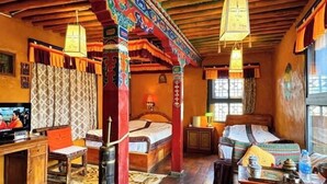 A traditional room with a bed, desk, and television. - Shambhala Palace Hotel (Lhasa)