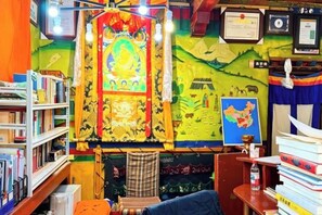 A room with a bookshelf, a map, a bed, and a desk with a chair. - Shambhala Palace Hotel (Lhasa)