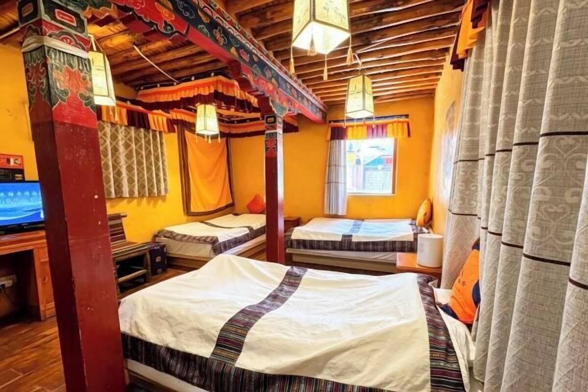 A traditional room with a bed, a desk with a computer, and a window with curtains.