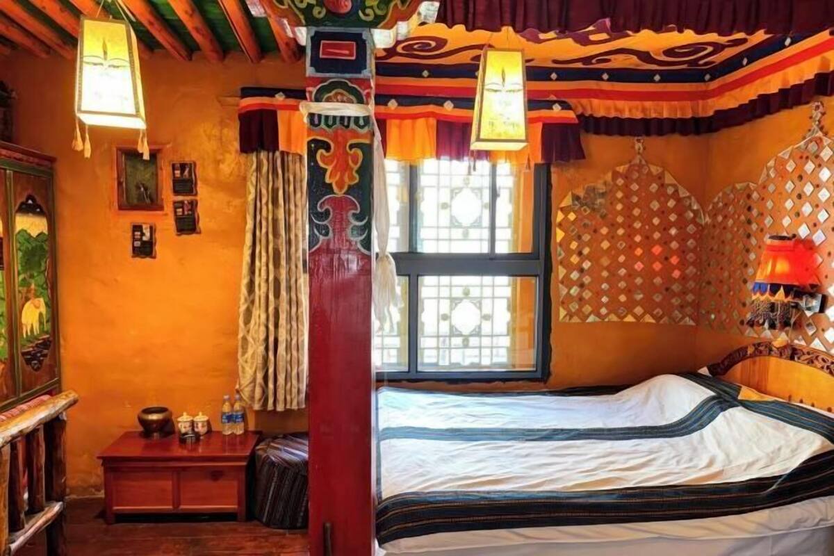 A traditional room with a bed, a window, and a wall with patterned decorations.