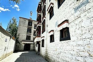 A narrow alleyway with a stone building, a wooden door, and a window with a dark frame. - Shambhala Palace Hotel (Lhasa)