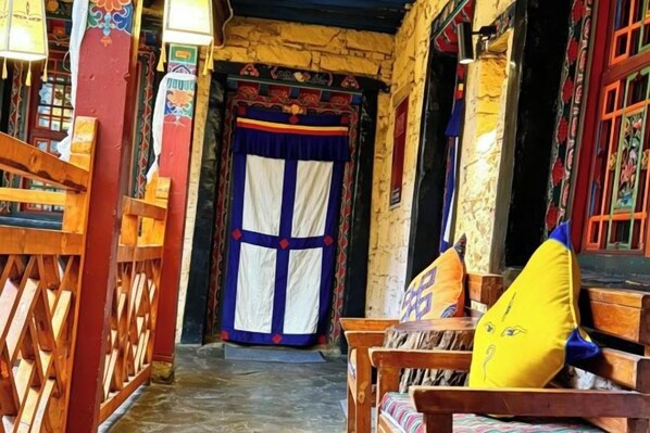 Un edificio tradicional con puerta de madera, bancos y pared de piedra.