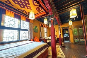 Una habitación tradicional con cama, ventanas y puerta.