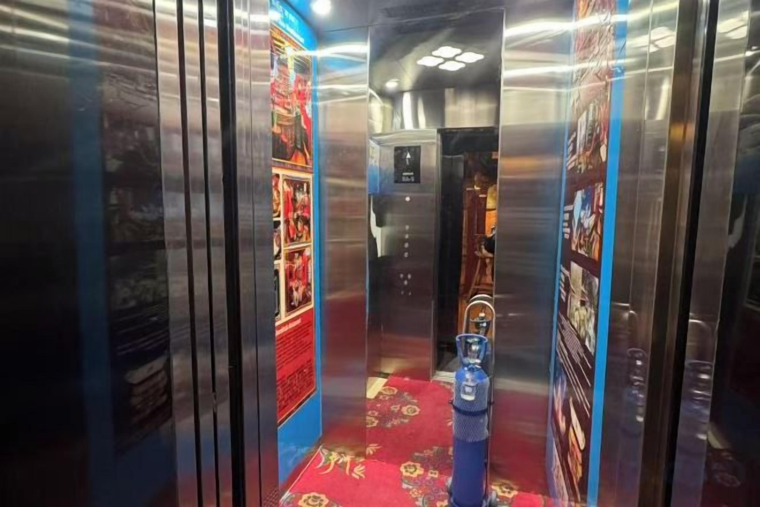 Un ascensor con alfombra roja y extintor azul.