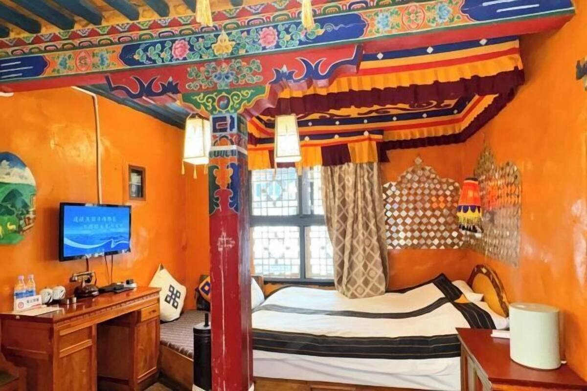 A room with a bed, a desk, a television, and a window with curtains.
