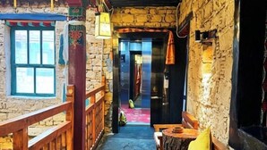 A narrow stone corridor with a wooden railing, a bench, and a door leading to another room. - Shambhala Palace Hotel (Lhasa)