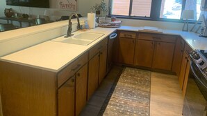 A modern kitchen with wooden cabinets, a large island with a sink, and a window providing natural light. - Spacious and Peaceful Location, Family and Pet Friendly (Mammoth Lakes)