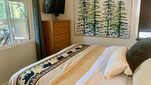 A bedroom with a bed, a dresser, a television, and a painting of trees. - Spacious and Peaceful Location, Family and Pet Friendly (Mammoth Lakes)