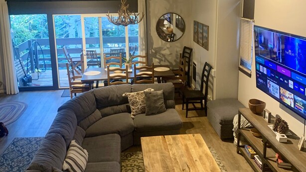 A modern living room with a sectional sofa, a wooden coffee table, and a television mounted on the wall. - Spacious and Peaceful Location, Family and Pet Friendly (Mammoth Lakes)