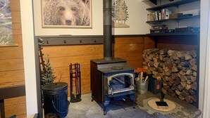 A cozy room with a wood-burning stove, a bookshelf, and a framed picture of a bear. - Spacious and Peaceful Location, Family and Pet Friendly (Mammoth Lakes)