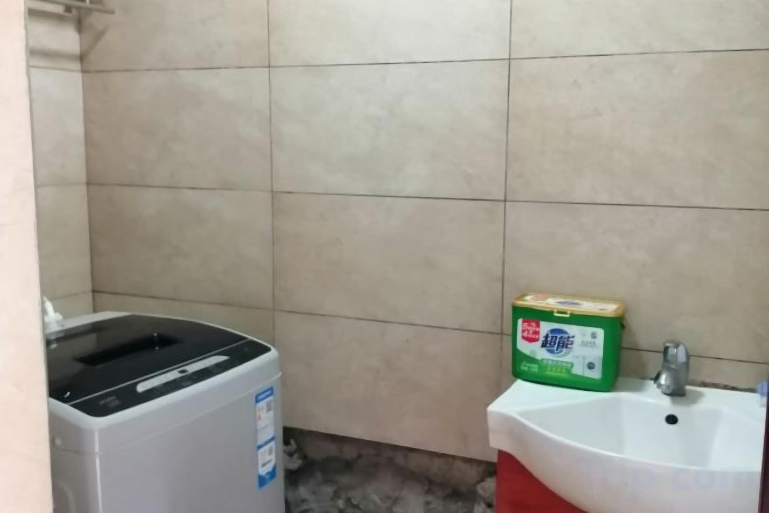 Ein Badezimmer mit einem weißen Waschbecken, einem Mülleimer und einer grünen Spülmittelkartusche.