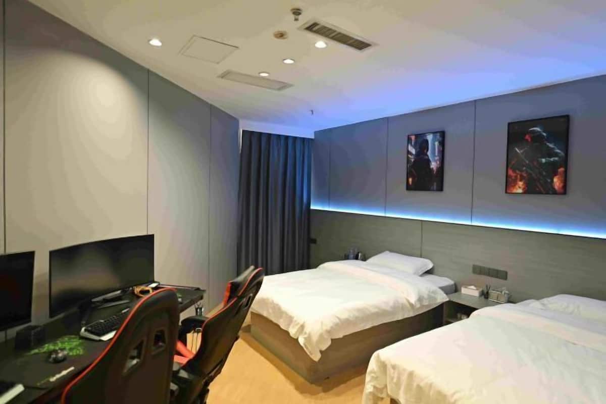 A hotel room with two beds, a desk with a computer, and a TV.