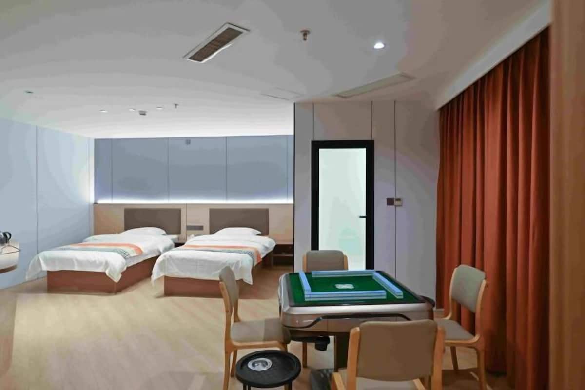 A hotel room with two beds, a desk with a pool table, and a large window.