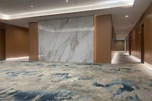 A hotel corridor with a marble wall, carpeted floor, and wooden doors. - Sihe Haichuan Hostel (Nanping)