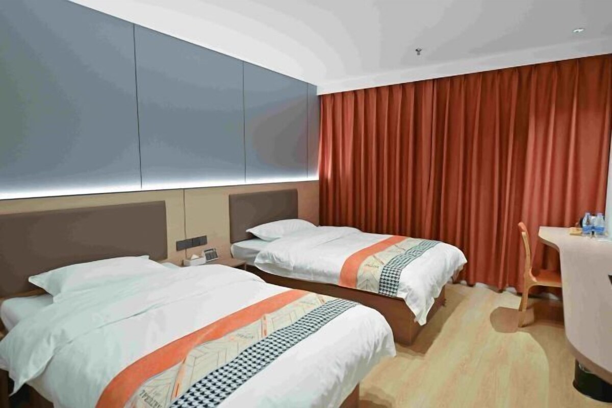 A hotel room with two beds, a desk, and a chair.
