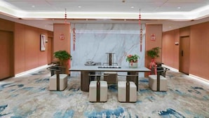 A conference room with a marble backdrop, a long table with chairs, and potted plants. - Sihe Haichuan Hostel (Nanping)