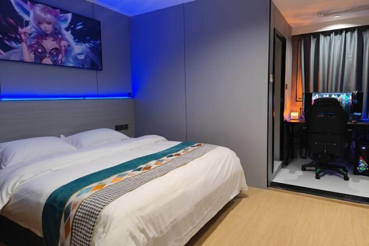 A hotel room with a bed, a desk with a computer, and a TV.